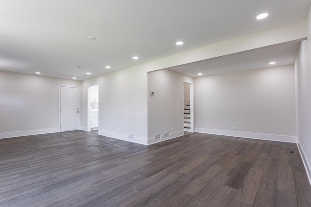 spare room featuring dark wood-style floors, stairway, baseboards, and recessed lighting