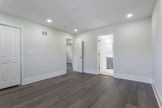 unfurnished bedroom featuring dark wood-style floors, baseboards, recessed lighting, connected bathroom, and a closet