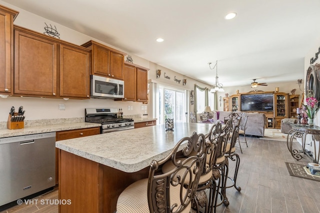 3313 Christopher Ln, Johnsburg, IL 60051 - kitchen with appliances with stainless steel finishes, open floor plan, brown cabinetry, ceiling fan, and light countertops