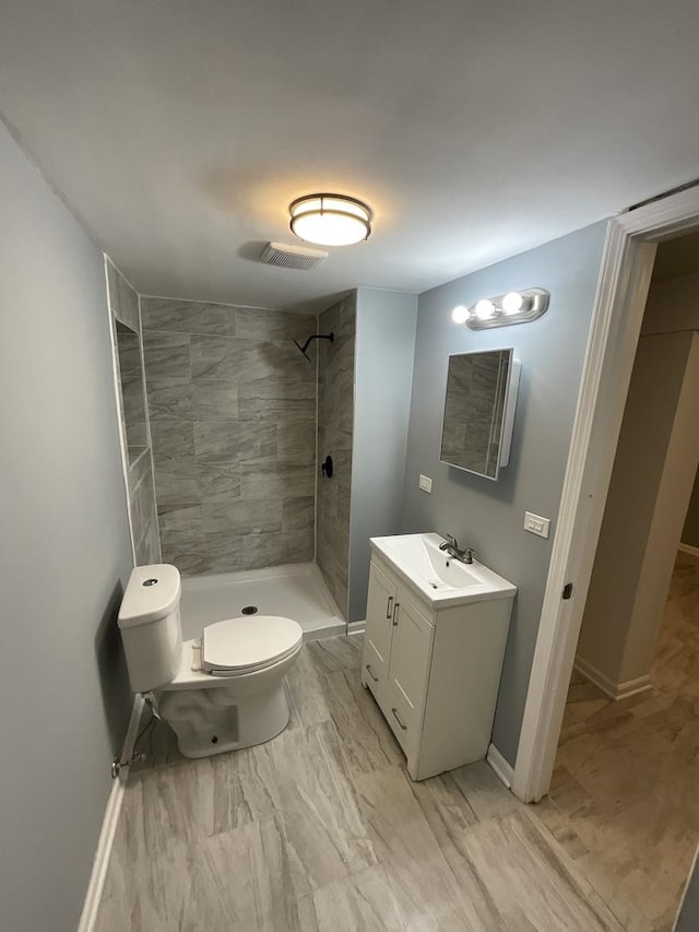 6954 S Prairie Ave, Chicago, IL 60637 - bathroom featuring vanity, tiled shower, toilet, baseboards, and marble look tiles