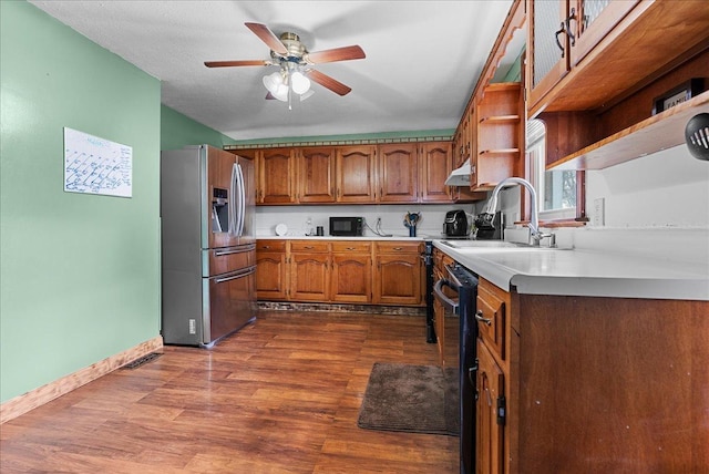 kitchen featuring stainless steel refrigerator with ice dispenser, a sink, open shelves, brown cabinetry, and light countertops