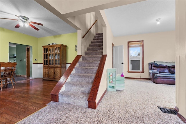 stairs featuring baseboards, ceiling fan, and wood finished floors