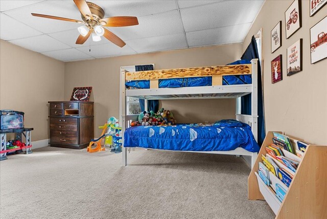 bedroom with a drop ceiling, carpet floors, and a ceiling fan