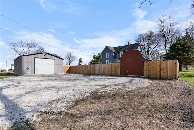 view of yard featuring fence, an outdoor structure, gravel driveway, and a detached garage