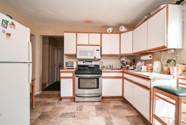 1423 Victoria Ave, North Chicago, IL 60064 - kitchen featuring white appliances, light countertops, white cabinets, and stone finish floors