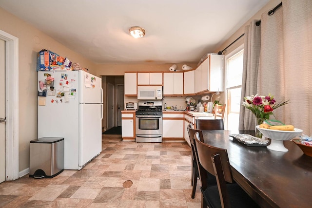 1423 Victoria Ave, North Chicago, IL 60064 - kitchen featuring white appliances, light countertops, a sink, stone finish flooring, and white cabinetry