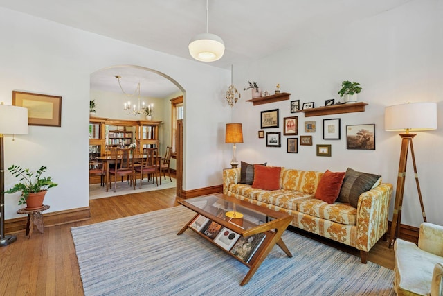 living room with arched walkways, baseboards, wood finished floors, and a chandelier