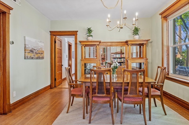 dining room featuring a chandelier, light wood-style floors, and baseboards