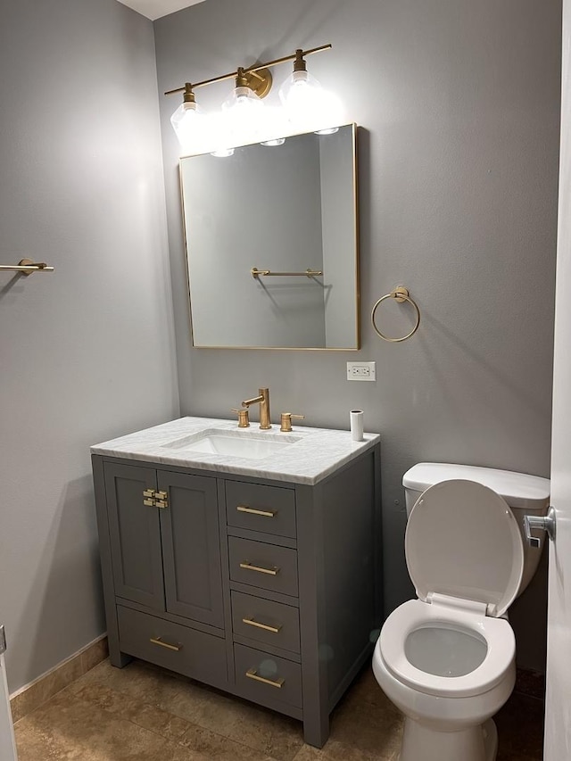 bathroom featuring vanity, toilet, and baseboards