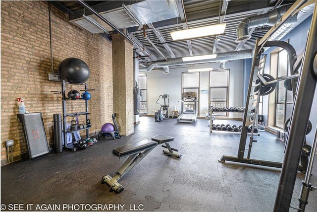 gym featuring a towering ceiling, brick wall, and gas water heater