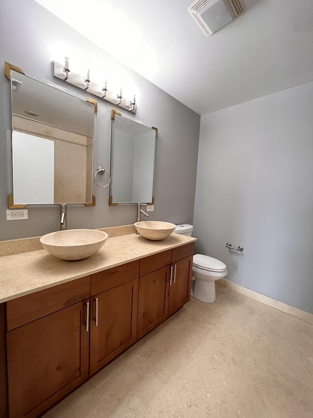 bathroom featuring double vanity, toilet, and baseboards