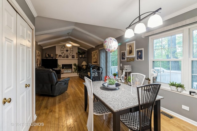772 Red Oak Dr, Bartlett, IL 60103 - dining space featuring wood-type flooring, lofted ceiling, a ceiling fan, a glass covered fireplace, and ornamental molding