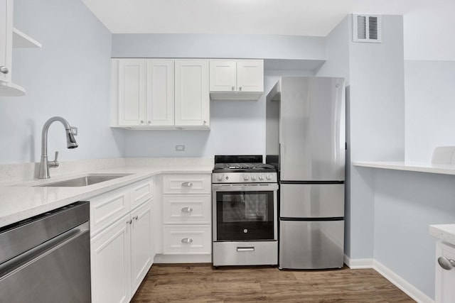 kitchen featuring appliances with stainless steel finishes, a sink, white cabinets, and dark wood-style floors