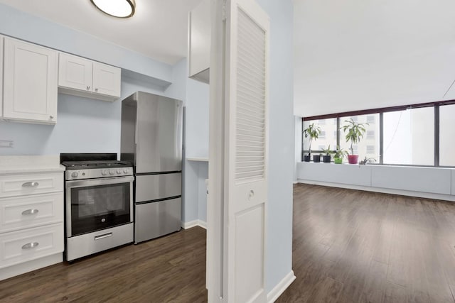 kitchen with appliances with stainless steel finishes, white cabinets, light countertops, dark wood-style flooring, and baseboards