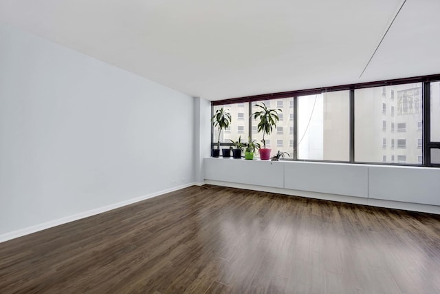 unfurnished room with wood finished floors, healthy amount of natural light, and baseboards
