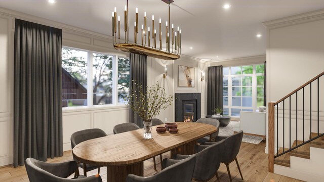 dining room with stairway, a glass covered fireplace, light wood-style floors, recessed lighting, and ornamental molding
