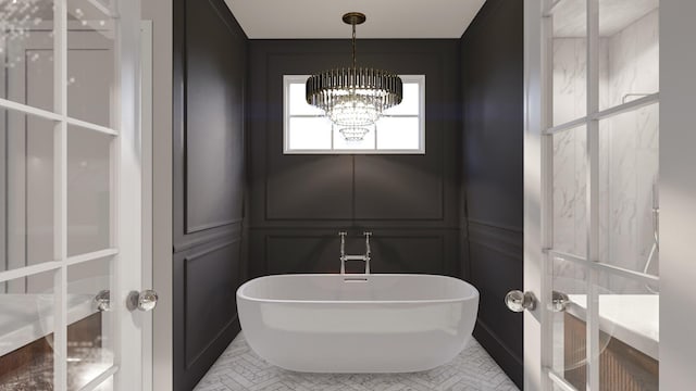 full bath featuring a freestanding bath, a chandelier, and a decorative wall