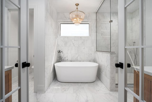 full bathroom featuring vanity, a soaking tub, marble look tiles, and french doors