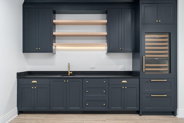 indoor wet bar with light wood finished floors and baseboards