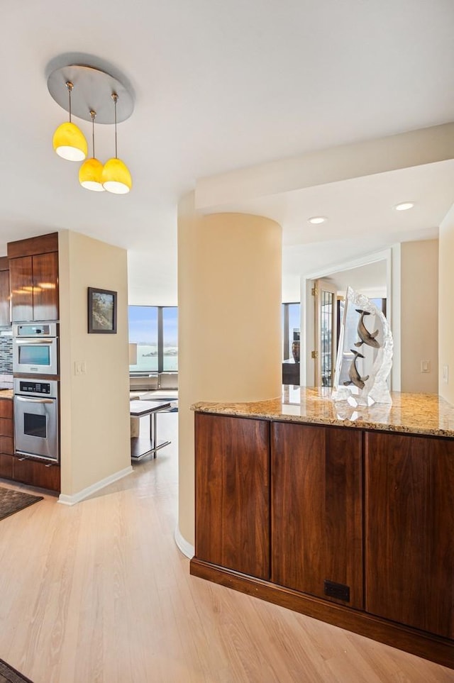 505 N Lake Shore Dr Unit 4907, Chicago, IL 60611 - kitchen featuring light wood finished floors, stainless steel double oven, light stone counters, decorative light fixtures, and baseboards