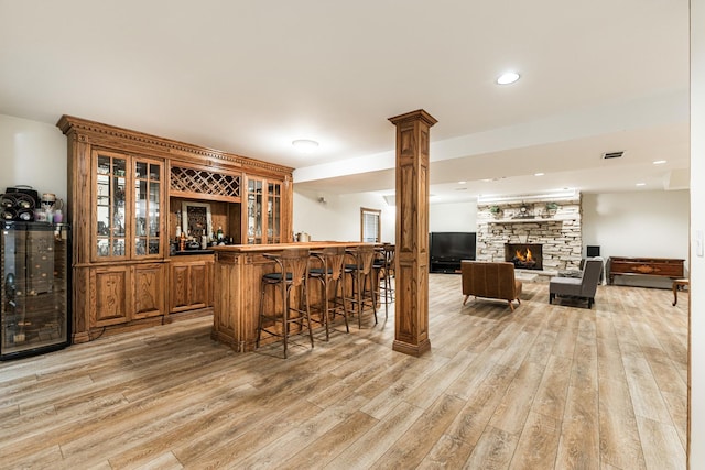 3113 Turnberry Rd, Saint Charles, IL 60174 - indoor bar featuring light wood-style floors, a stone fireplace, wine cooler, ornate columns, and recessed lighting