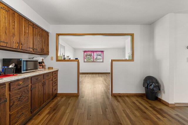 849 N Piatt St, Bement, IL 61813 - kitchen featuring stainless steel microwave, wood finished floors, light countertops, baseboards, and brown cabinets