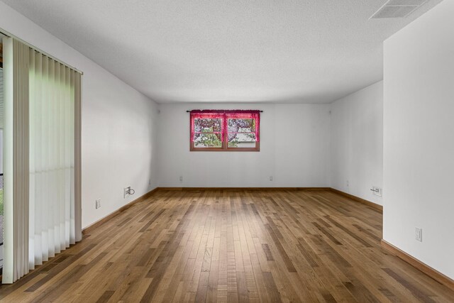 849 N Piatt St, Bement, IL 61813 - spare room featuring wood-type flooring, baseboards, and a textured ceiling
