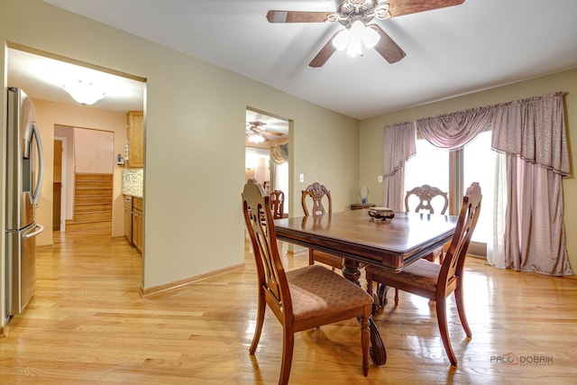 dining area with ceiling fan, light wood-type flooring, stairway, and baseboards
