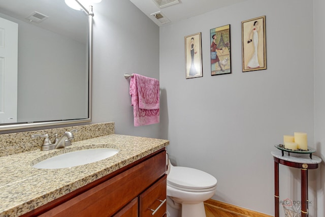 bathroom with vanity, toilet, wood finished floors, and baseboards