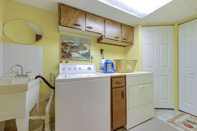 clothes washing area featuring cabinet space and washer and clothes dryer