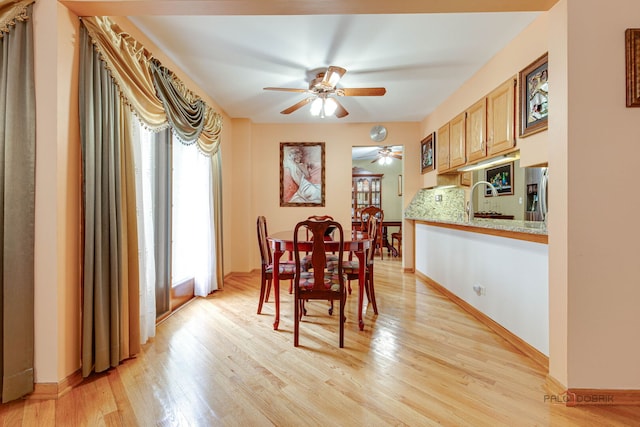 dining room with ceiling fan, light wood-type flooring, and baseboards