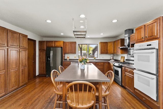 112 Braemar Dr, Elk Grove Village, IL 60007 - kitchen featuring appliances with stainless steel finishes, wall chimney range hood, brown cabinets, dark wood-type flooring, and recessed lighting