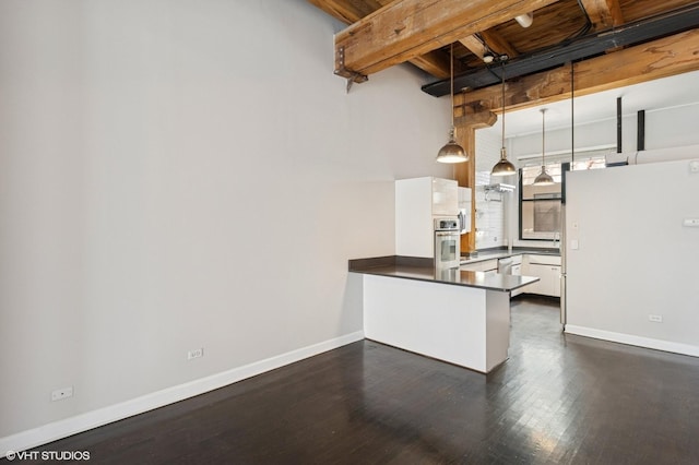 kitchen featuring stainless steel appliances, dark countertops, a peninsula, white cabinetry, and dark wood finished floors