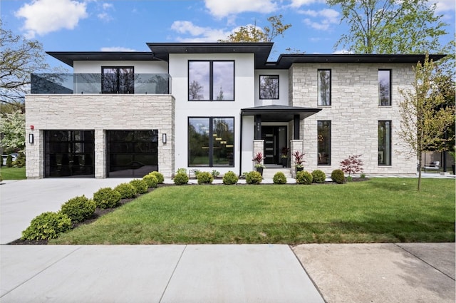 modern home with stone siding, driveway, an attached garage, a front lawn, and stucco siding