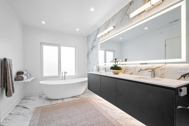 bathroom featuring marble finish flooring, recessed lighting, a soaking tub, and double vanity
