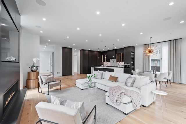 living area with light wood-style floors, a chandelier, recessed lighting, and a large fireplace