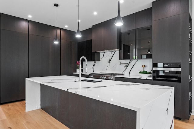 kitchen featuring modern cabinets, light wood finished floors, a spacious island, decorative light fixtures, and recessed lighting