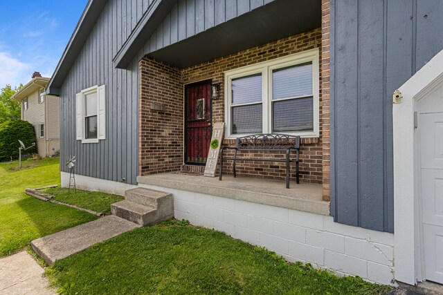 2717 E Main St, Decatur, IL 62521 - property entrance featuring board and batten siding, a yard, brick siding, and covered porch