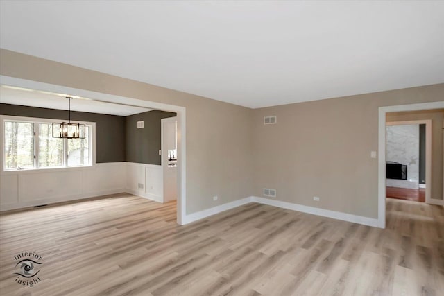 2639 E Shady Grove Ct, Crete, IL 60417 - empty room featuring a chandelier, light wood-style flooring, and wainscoting