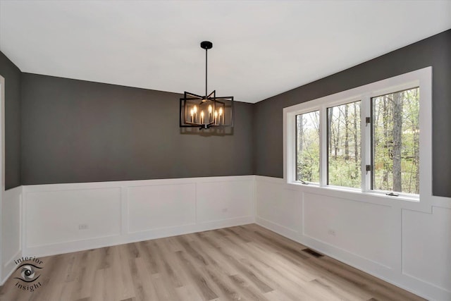 2639 E Shady Grove Ct, Crete, IL 60417 - empty room featuring a chandelier, a wainscoted wall, light wood-style floors, and a decorative wall