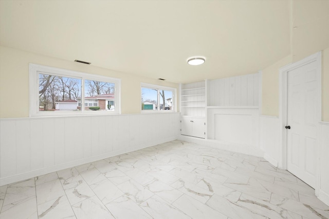 236 Early St, Park Forest, IL 60466 - spare room with wainscoting, marble look tile flooring, built in shelves, and a decorative wall