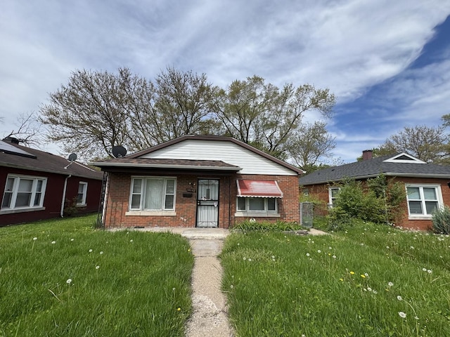 bungalow with brick siding and a front yard