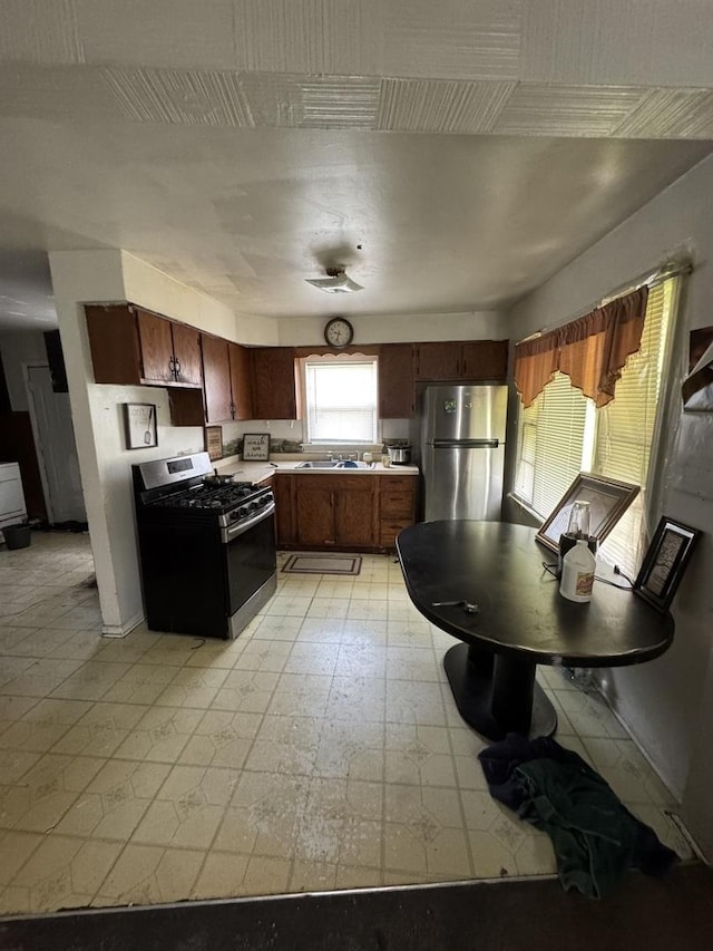 kitchen featuring stainless steel appliances, a sink, light floors, and light countertops