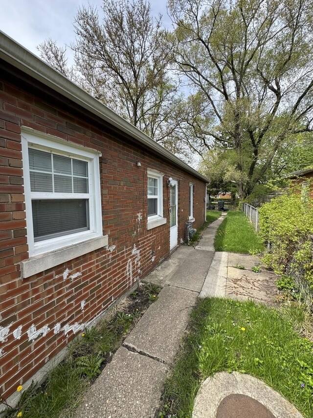 view of side of home featuring brick siding and fence
