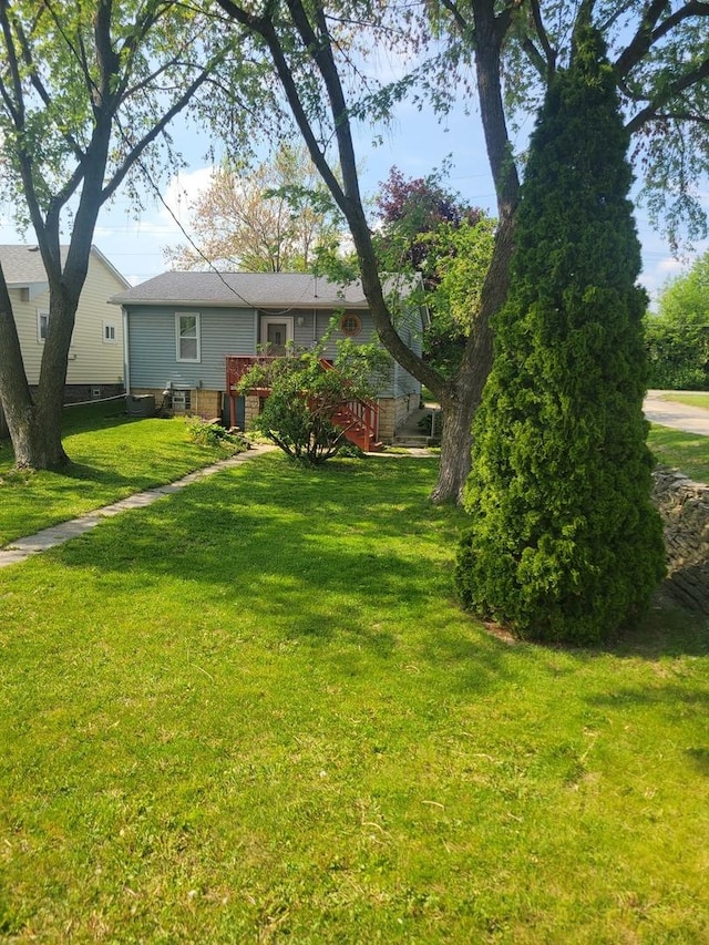 view of green lawn featuring a deck