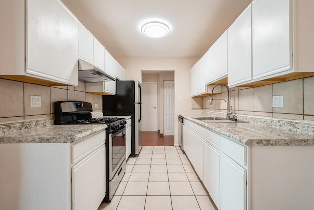kitchen with appliances with stainless steel finishes, under cabinet range hood, a sink, tasteful backsplash, and light countertops