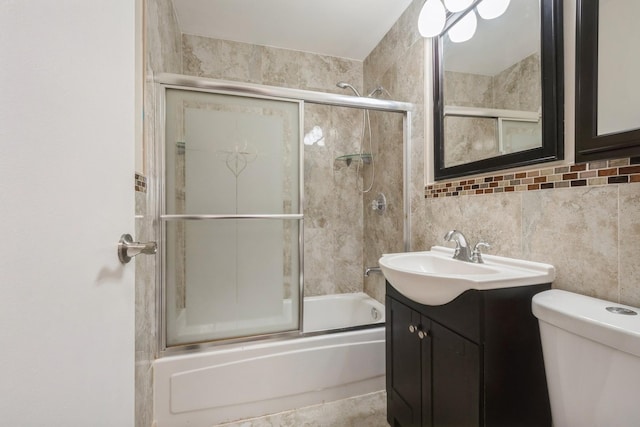 full bath with shower / bath combination with glass door, tile walls, toilet, vanity, and tasteful backsplash