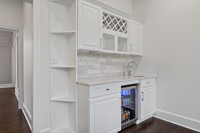 indoor wet bar with backsplash, wine cooler, dark wood-type flooring, and baseboards