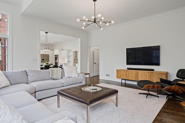 living area featuring a chandelier, dark wood-type flooring, crown molding, and baseboards