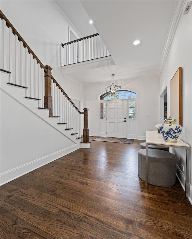 foyer with stairs, crown molding, wood finished floors, a chandelier, and recessed lighting